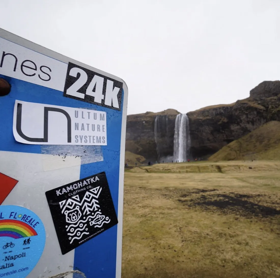 A UNS sticker on a road sign with the Seljalandsfoss waterfall behind it